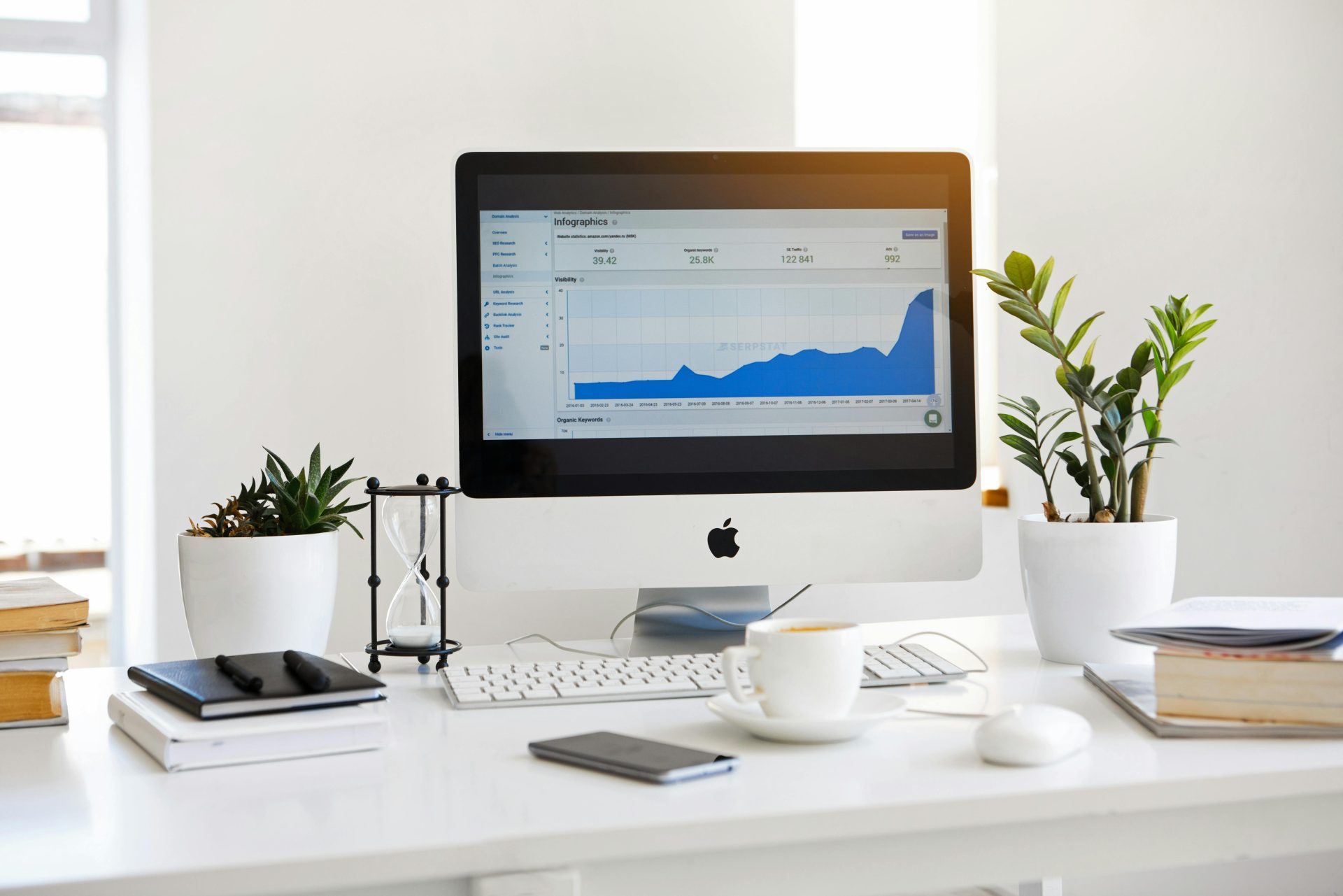 Ein sauberer, moderner Arbeitsplatz mit einem Desktop mit Analysefunktionen auf dem Bildschirm und Pflanzen für ein frisches Aussehen.