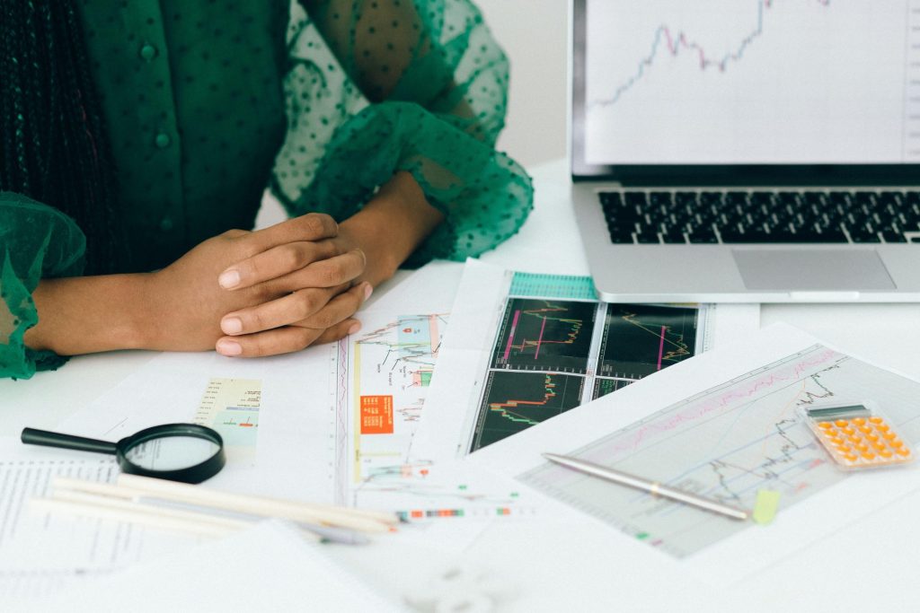 Eine Person analysiert an einem Schreibtisch Finanzdiagramme und -grafiken, um die Handelsaktivität eines Unternehmens anzuzeigen.